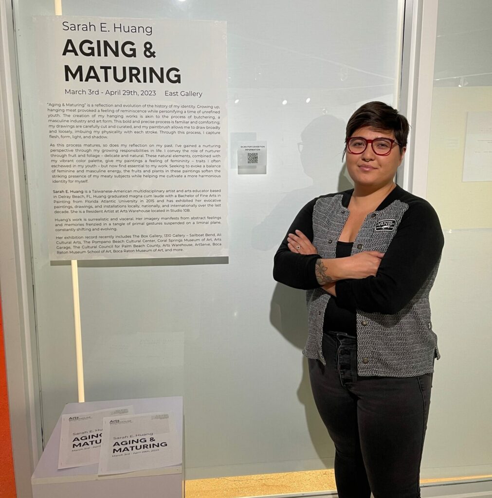 Sarah E. Huang posing in front of her "Aging & Maturing Exhibition" at the Arts Warehouse
